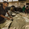 Workers cut the dough into small pieces. The small pieces will then be rolled up and put into trays for baking. Photographer: Arnav Rastogi/ Fseven Photographers